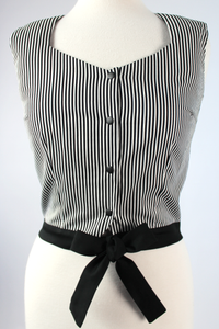 Close up of top, Top on mannequin, Pictured from the front, Sleeveless top, Stiped material, Black waist band that ties into a bow